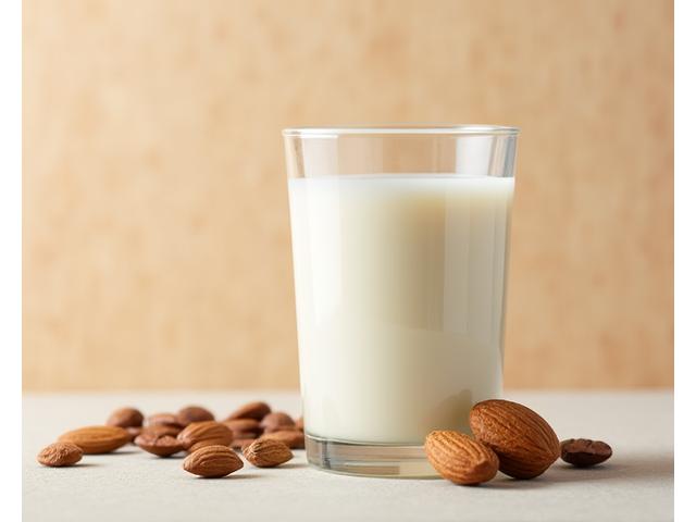 A glass of almond milk next to coffee beans, suggesting a delicate and nutty flavour.